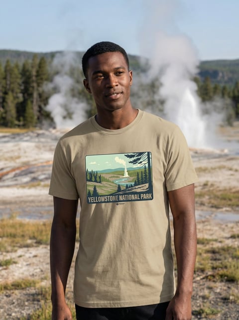 Man wearing beige Yellowstone National Park t-shirt standing in front of geyser and geothermal features at Yellowstone